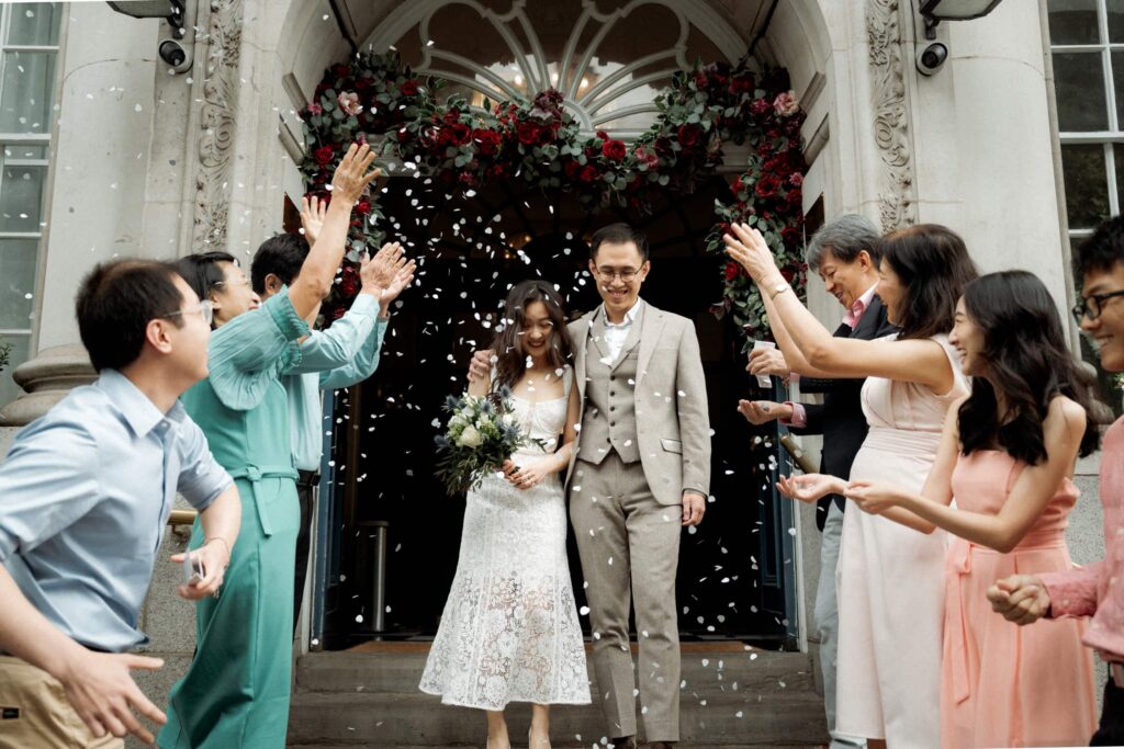 Bride and groom exit Chelsea Town Hall in London as guests throw confetti, captured by a London wedding photographer.