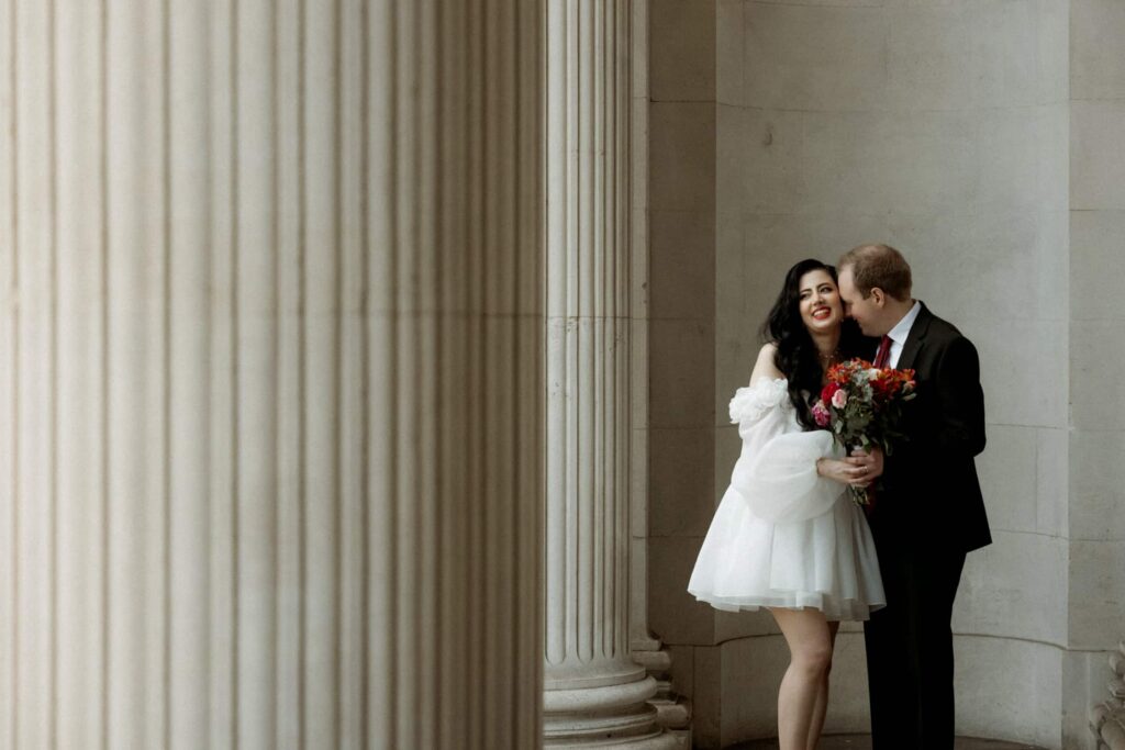 Bride and groom sharing a moment by columns at Old Marylebone Town Hall, captured by a London wedding photographer.
