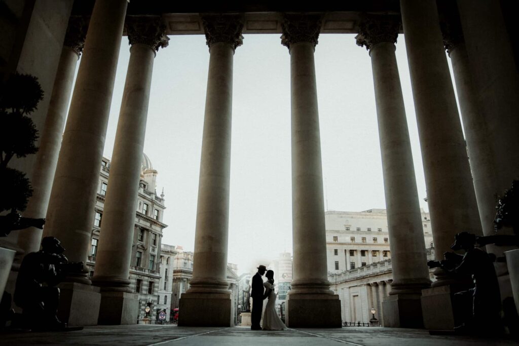 Silhouetted couple embracing beneath grand columns at Royal Exchange London, captured by a London wedding photographer.