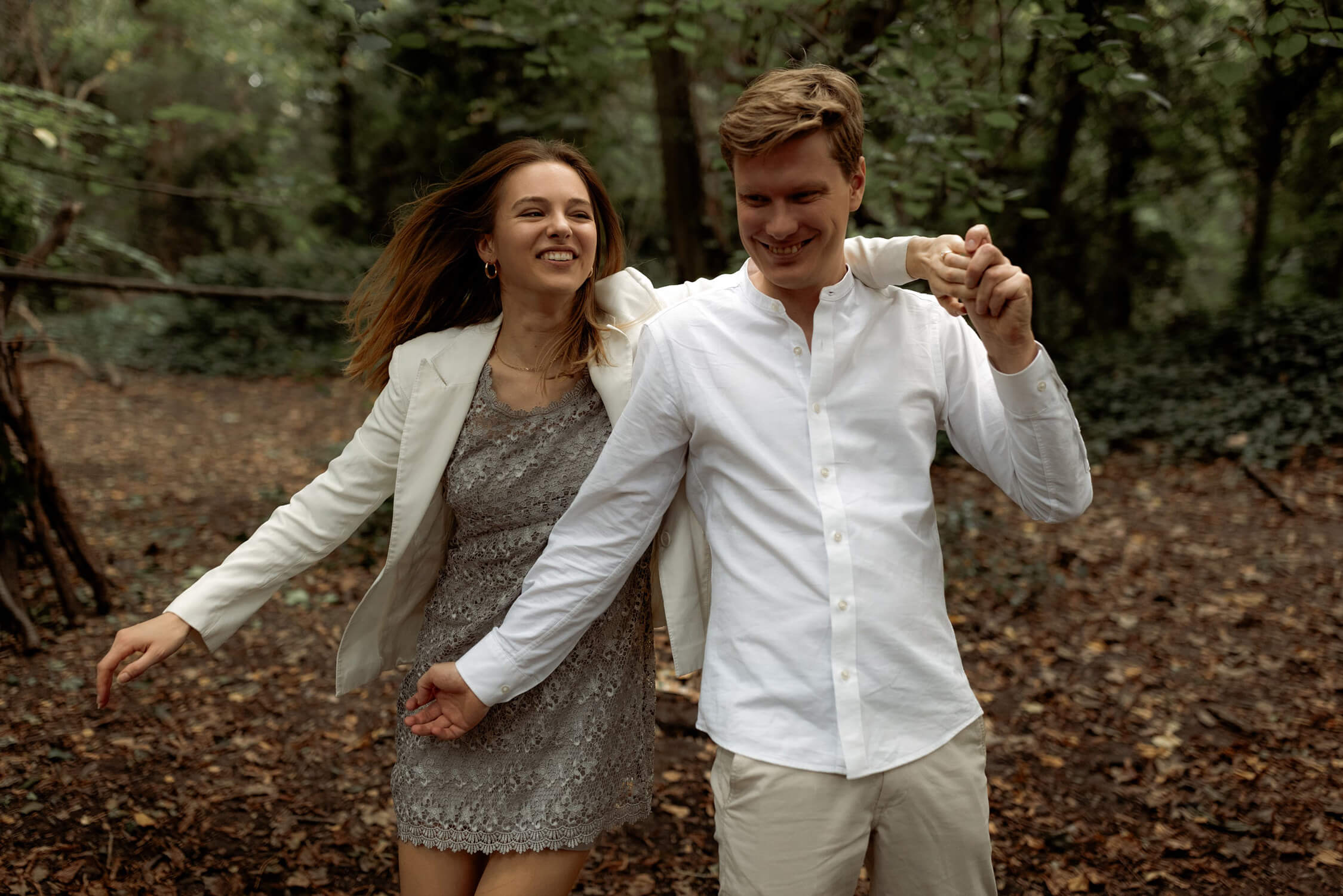 Couple walking hand in hand through woodland at Hampstead Heath, a best place to elope in London.
