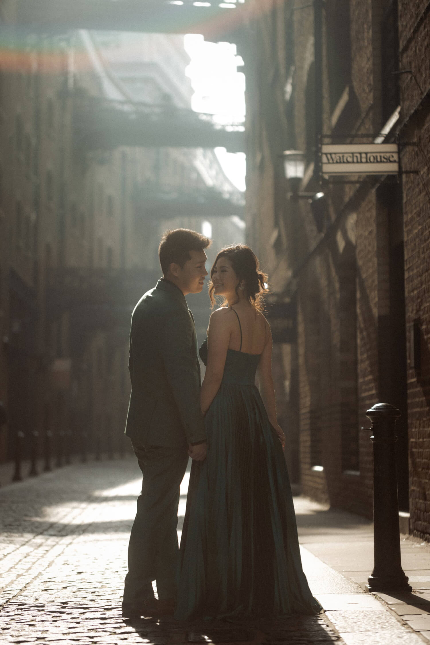Couple standing in sunlit Shad Thames alley, one of the best places to elope in London with historic cobbled streets.