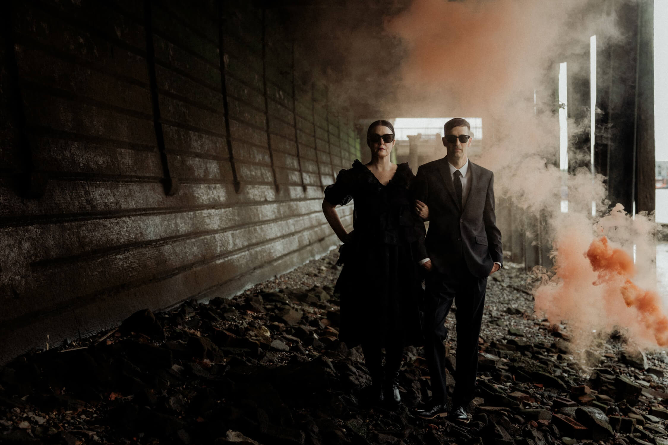 Stylish couple walking under Tower Bridge with dramatic smoke, one of the best places to elope in London.