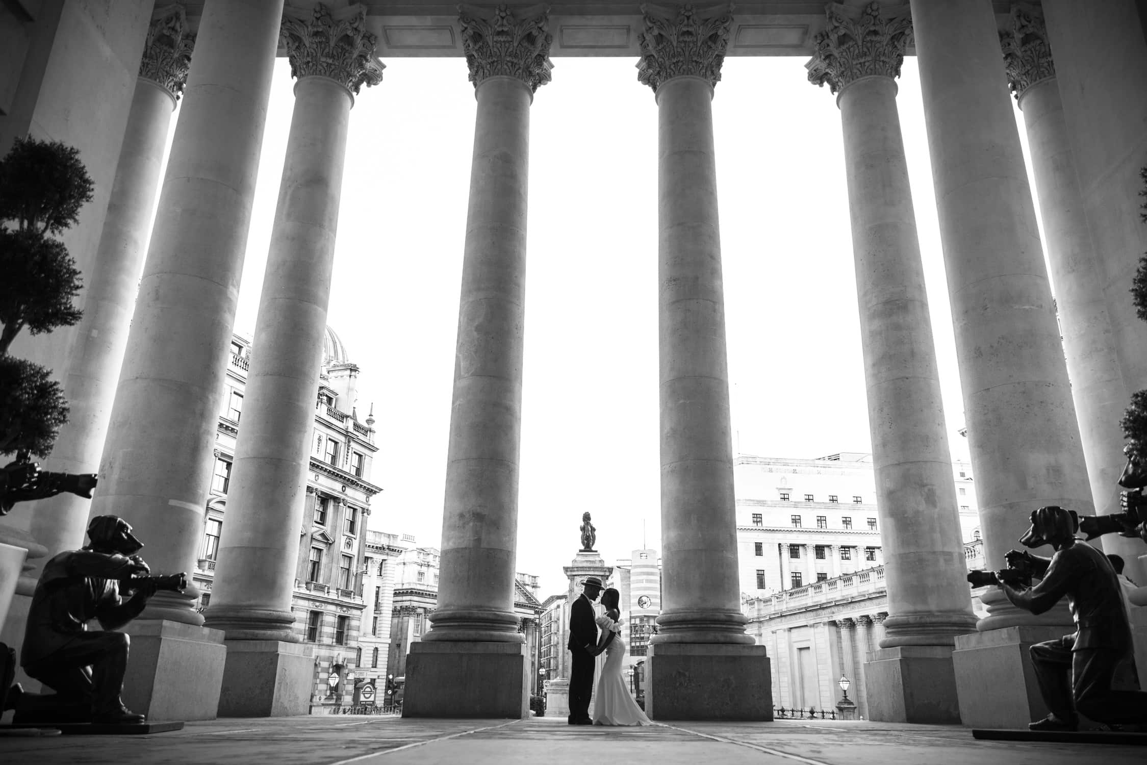 Couple standing beneath grand columns at Royal Exchange during a pre-wedding photoshoot in London.