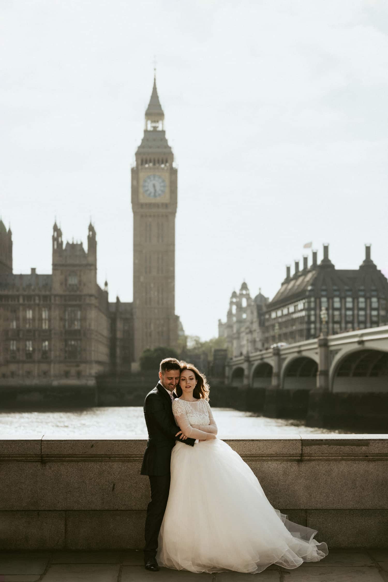 Couple embracing by the River Thames with Big Ben in the background during a pre-wedding photoshoot in London.